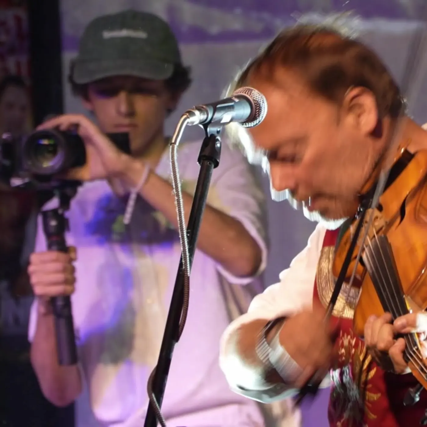 Toni filmt beim Ursprung Buam Fest, im Vordergrund ein Geiger am Mikrofon